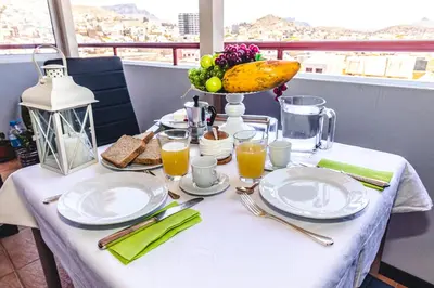 a table with plates of food and a bowl of fruit at Criola Vistamar in Mindelo