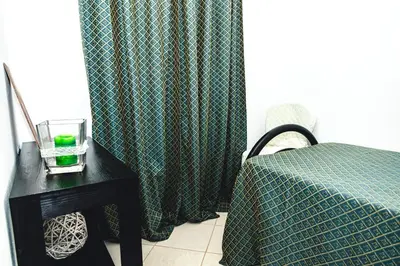 a bedroom with a bed and a table with a green curtain at Criola Vistamar in Mindelo