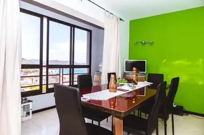 a dining room with green walls and a table and chairs at Criola Vistamar in Mindelo