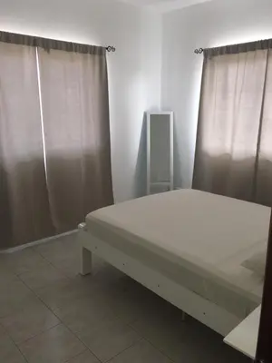 a bed in a room with two windows with curtains at Apartamento Coral in Santa Maria