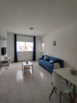 a living room with a blue couch and a table at Apartamento Coral in Santa Maria