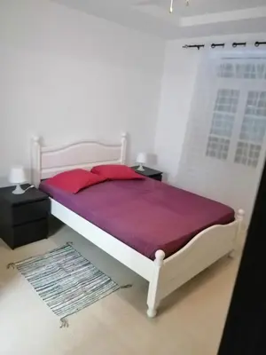 a bedroom with a white bed with a purple blanket at Casas do Cinema I in Mindelo