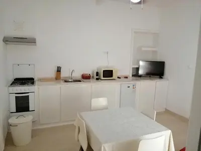 a white kitchen with a table and a microwave at Casas do Cinema I in Mindelo