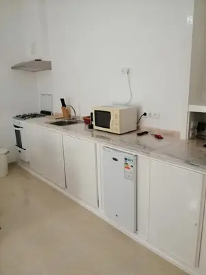 a kitchen with white cabinets and a microwave on a counter at Casas do Cinema I in Mindelo