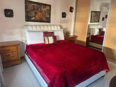 a bedroom with a large bed with a red blanket at YOUR HOME AWAY FROM HOME in Praia