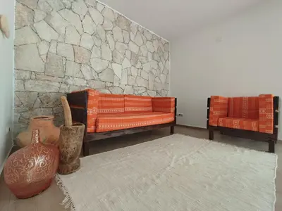 a living room with two orange couches and a stone wall at Casa Djarmai Apartments in Vila do Maio