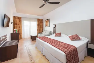 a hotel room with a large bed and a chair at Hotel Riu Funana - All Inclusive in Santa Maria