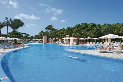 a large swimming pool with chairs and umbrellas at a resort at Hotel Riu Cabo Verde - Adults Only - All Inclusive in Santa Maria