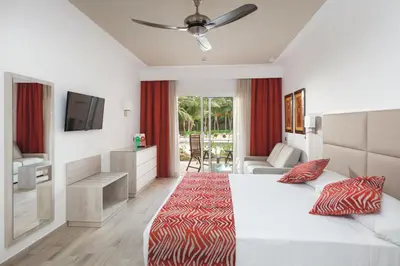 a bedroom with a bed and a television and a couch at Hotel Riu Cabo Verde - Adults Only - All Inclusive in Santa Maria