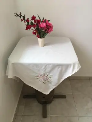 a table with a white table cloth and a vase of flowers at Casa Familiar Gilda in Ribeira Grande
