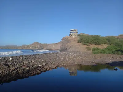 a reflection of a lighthouse on a rocky beach at Casa Fabrice in Ribeira da Prata