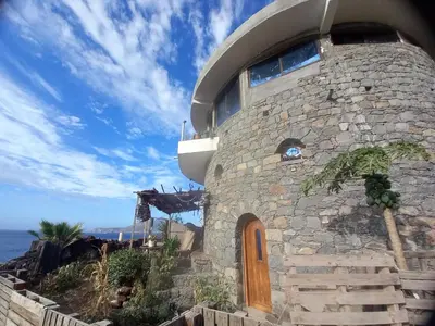 a stone building with a wooden door and the ocean at Casa Fabrice in Ribeira da Prata