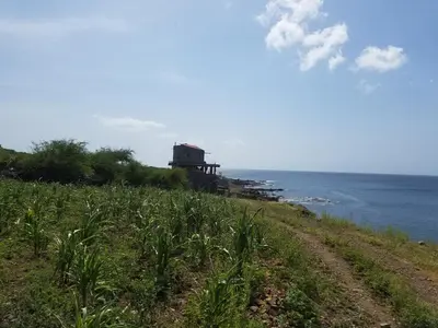 a dirt road next to the ocean with a building at Casa Fabrice in Ribeira da Prata