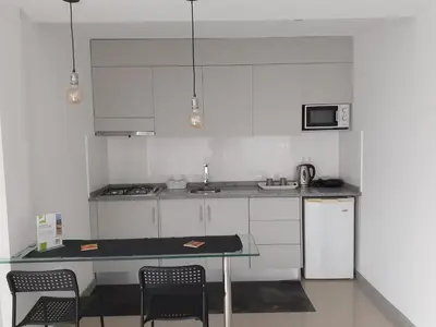 a kitchen with white cabinets and a table with chairs at Apto T1 Sweet Home in Praia