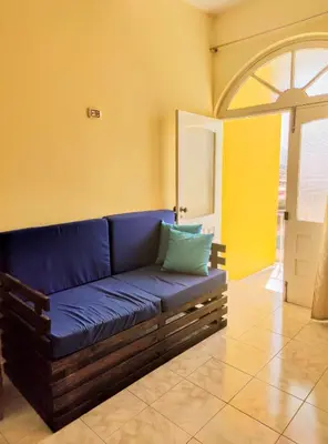 a blue couch in a room with a yellow wall at Casa Bom Dia in Mindelo