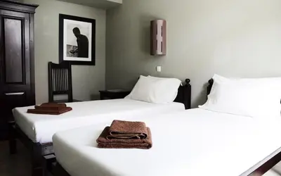 two beds in a hotel room with a towel on the bed at Casa Colonial in Mindelo