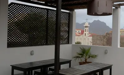 a table and benches in a room with a view of a church at Casa Colonial in Mindelo