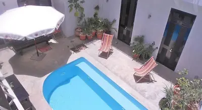 a swimming pool with two chairs and a table and a house at Casa Colonial in Mindelo