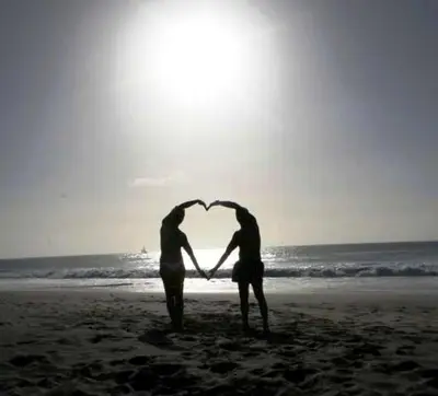 two people standing on the beach forming a heart at Ibiscus in Santa Maria