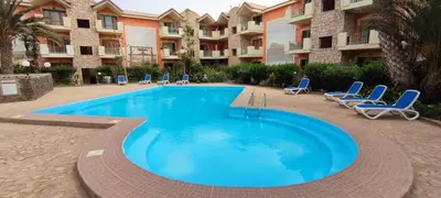 a large swimming pool with chairs and a building at Sal Service djasal residence with pool in Santa Maria