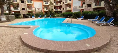 a large swimming pool with chairs and a building at Sal Service djasal residence with pool in Santa Maria