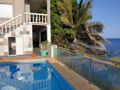 a house with a swimming pool next to the ocean at Cactus Guest House in Cidade Velha