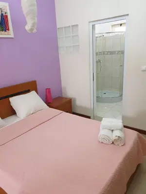 a bedroom with a bed and a shower and towels at Cactus Guest House in Cidade Velha