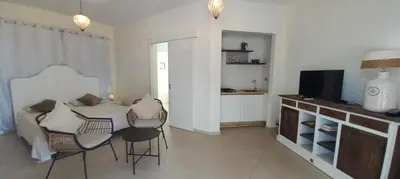 a living room with a table and chairs and a television at Villa Cristina Alojamento, Praia de Chaves, Boa Vista, Cape Verde, WI-FI in Sal Rei