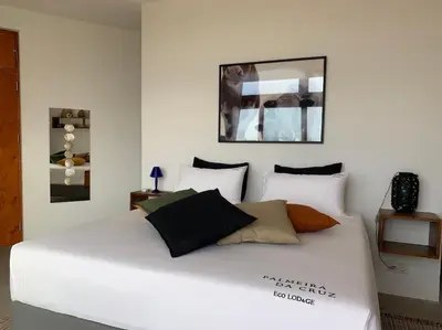 a white bed with pillows on it in a room at Palmeira Da Cruz EcoLodge in Chã da Igreja
