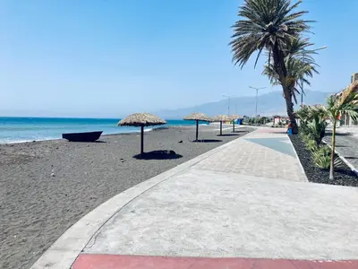 a walkway on a beach with umbrellas and the ocean at Pedra de Rala in Porto Novo