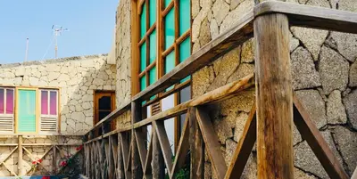 a wooden railing next to a stone building at Pedra de Rala in Porto Novo
