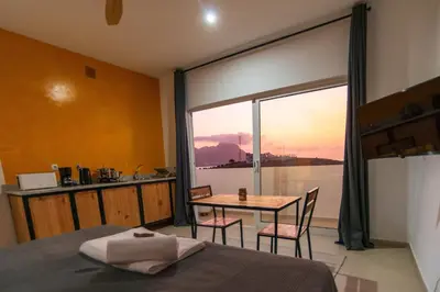 a room with a bed and a table and a window at Apartamento Zinha Amwilla Guesthouse in Mindelo