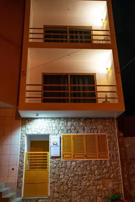 a building with a yellow door and a balcony at Apartamento Zinha Amwilla Guesthouse in Mindelo