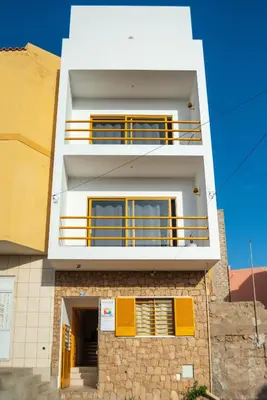 a white building with yellow balconies on it at Apartamento Zinha Amwilla Guesthouse in Mindelo