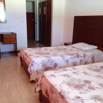 a hotel room with two beds and a dresser at Residencial Laginha in Mindelo