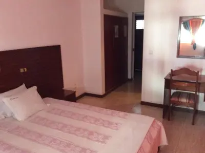 a bedroom with a bed and a table and a desk at Residencial Laginha in Mindelo