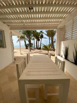 a wooden table and chairs on a patio with the beach at Villa Nº 25 Alfredo Marchetti Suites on the Beach,Praia de Chaves BV in Cabeçadas