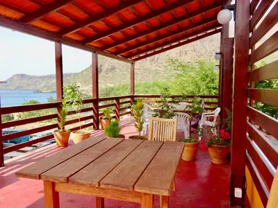 a wooden table on a porch with potted plants at Apartment with sea view near the beach and the village center! in Tarrafal