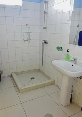 a white tiled bathroom with a sink and a shower at Apartment with sea view near the beach and the village center! in Tarrafal