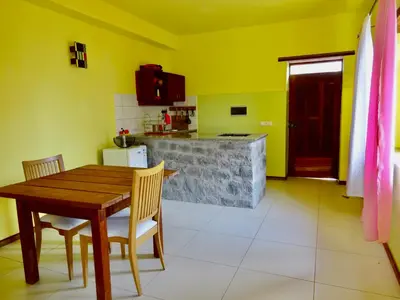 a kitchen with yellow walls and a wooden table and chairs at Apartment with sea view near the beach and the village center! in Tarrafal