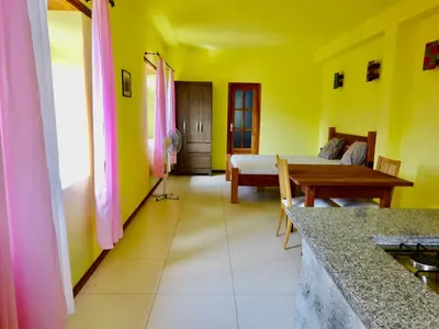 a room with yellow walls and a bed and a table at Apartment with sea view near the beach and the village center! in Tarrafal