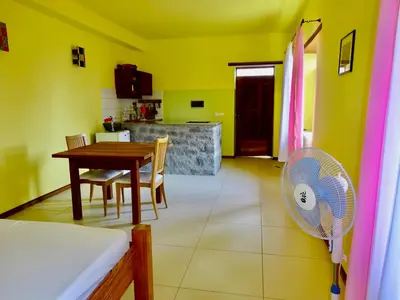 a room with a table and a kitchen with a fan at Apartment with sea view near the beach and the village center! in Tarrafal