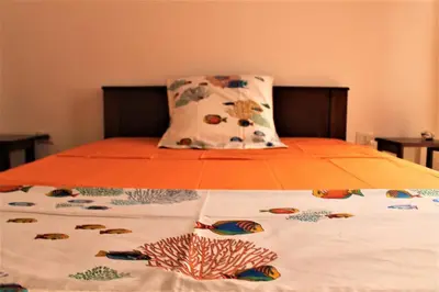 a bed with an orange comforter and pillows on it at African Sunset in Sal Rei