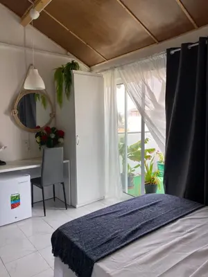 a bedroom with a bed and a desk and a window at Christian Place in Praia