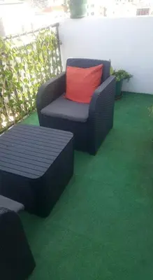 a chair with a red pillow sitting on a green floor at Christian Place in Praia