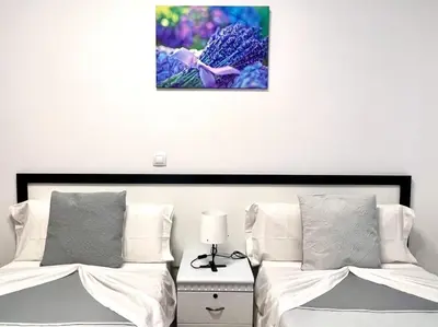 a bedroom with two beds and a painting on the wall at DAISAL APARTMENT - 2 bedroom apartment with balcony near the beach & city center in Santa Maria