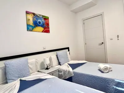 a bedroom with two beds and a painting on the wall at DAISAL APARTMENT - 2 bedroom apartment with balcony near the beach & city center in Santa Maria
