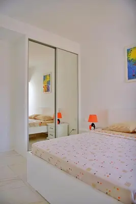 a white bedroom with two beds and a mirror at Duarte Apartments - Laginha in Mindelo
