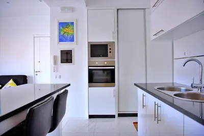 a white kitchen with a sink and a microwave at Duarte Apartments - Laginha in Mindelo
