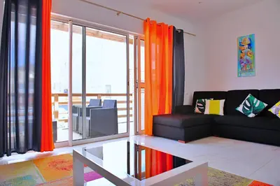 a living room with a black couch and orange curtains at Duarte Apartments - Laginha in Mindelo